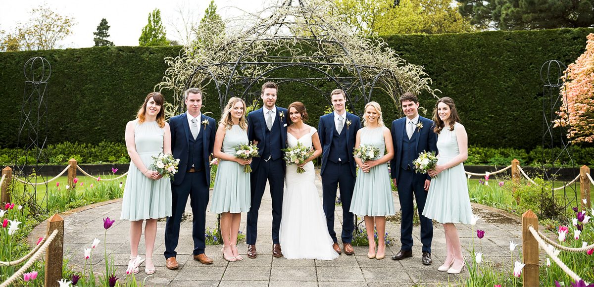 Bride and groom with their bridesmaids and groomsmen in the gardens of Gaynes Park