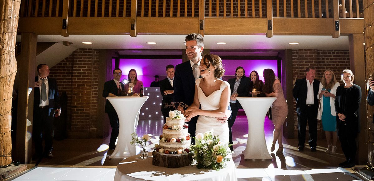Bride and groom cutting the cake while guests watch
