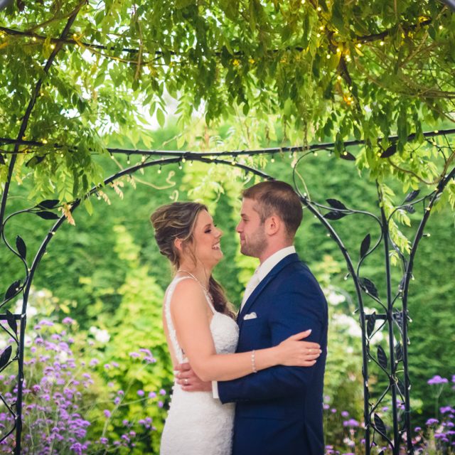 Newlyweds take a moment together under the wrought iron Pavilion covered in foliage