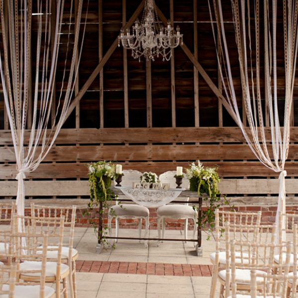 Chairs are dressed in white chair covers for this outside wedding ceremony in the Gather Barn