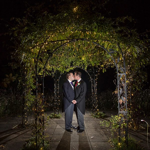The newlyweds share a kiss under the romantically lit iron pavilion perfect for wedding photos
