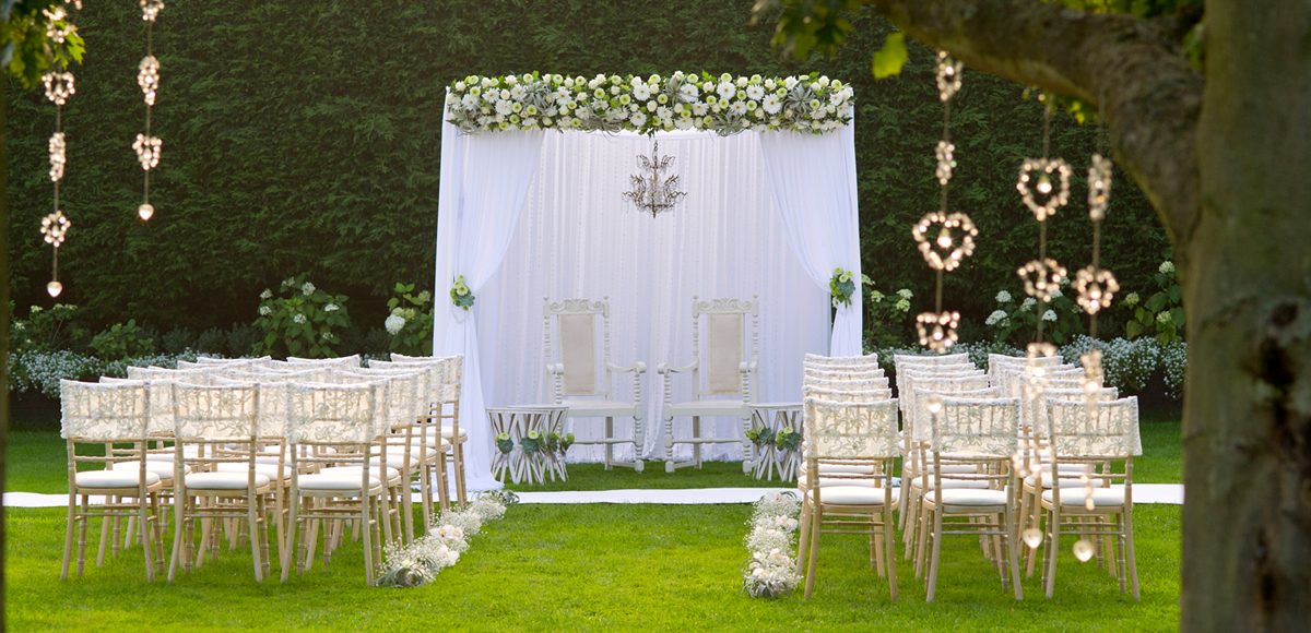 Chairs are neatly lined in rows in front of a white canopy for the outside wedding ceremony