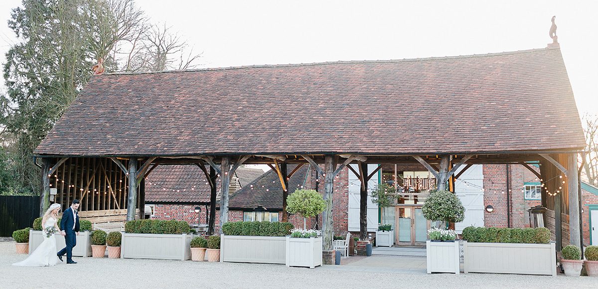 A happy couple stroll hand in hand past the Gather Barn which is perfect for outdoor weddings