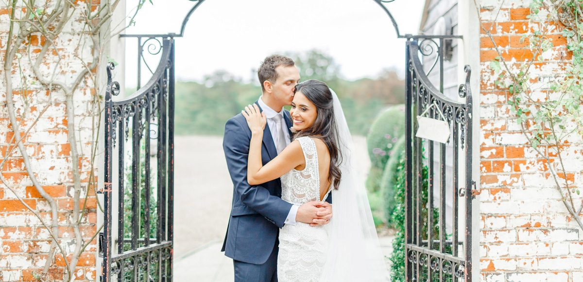 For a stunning wedding photograph the newlyweds stand in front of the gates on The Long Walk at Gaynes Park