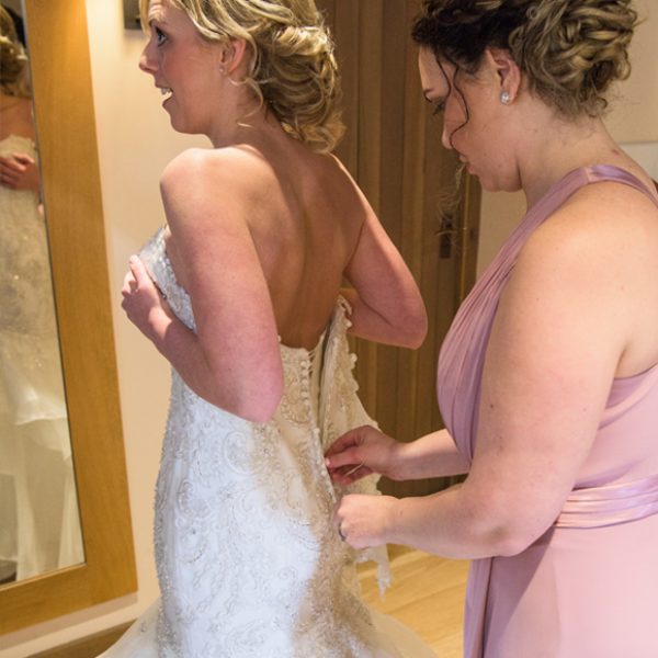 A bridesmaid helps the bride with last minute preparations before the wedding ceremony
