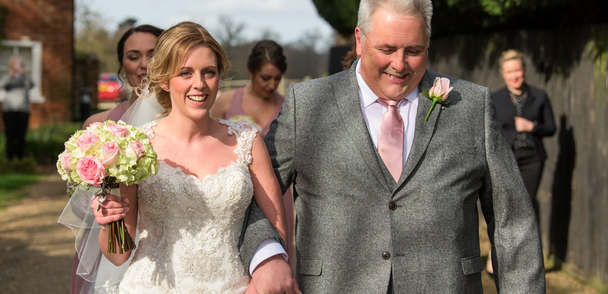 The bride and her father walk towards the wedding ceremony for a spring wedding at Gaynes Park
