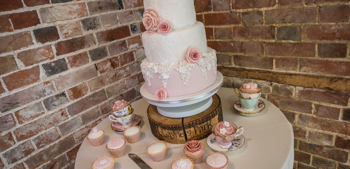 A three-tiered wedding cake was adorned with pink and white icing flowers for a spring wedding at Gaynes Park
