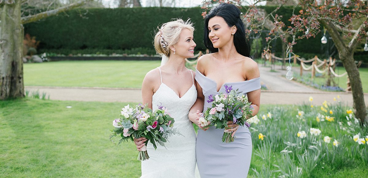 The bride and her bridesmaid enjoy a moment in the walled gardens at Gaynes Park in Essex