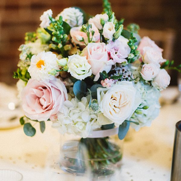 A jar of dusty pink roses adds elegance to a vintage wedding at Gaynes Park