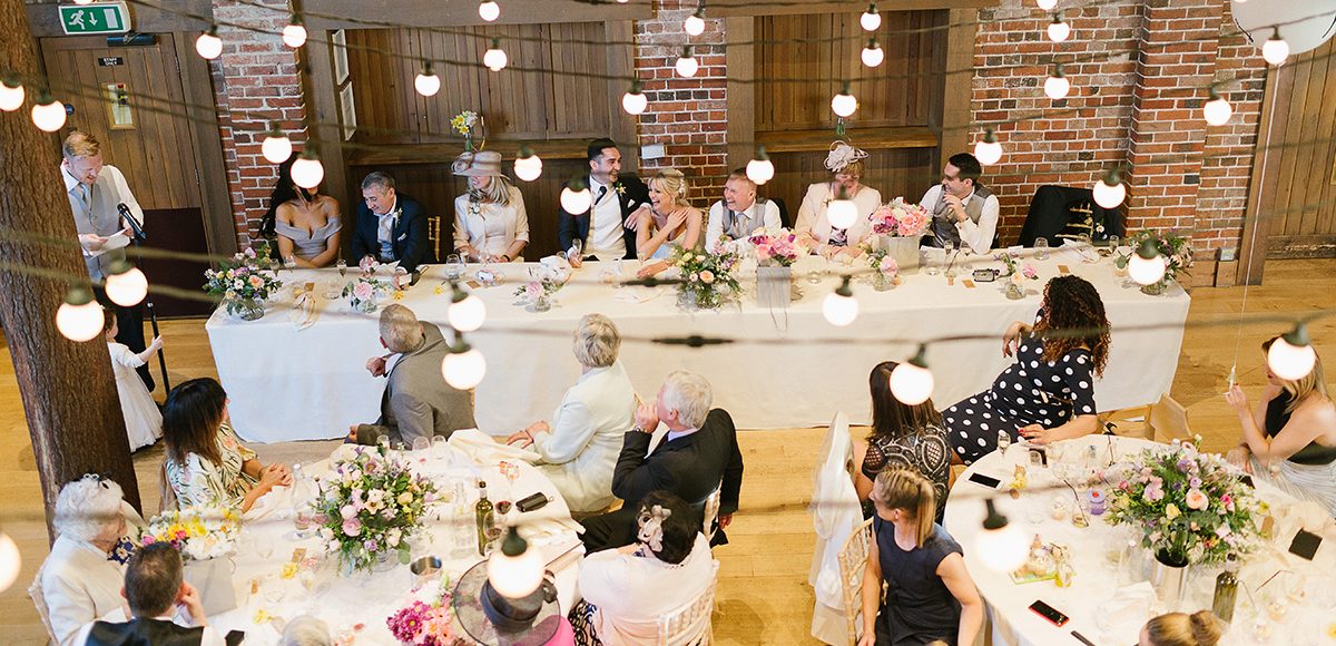 At the wedding reception in the Mill Barn at Gaynes Park in Essex guests enjoy the speech from the best man