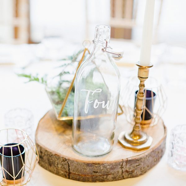 The newlyweds used glass bottles as table numbers for this rustic wedding at Gaynes Park