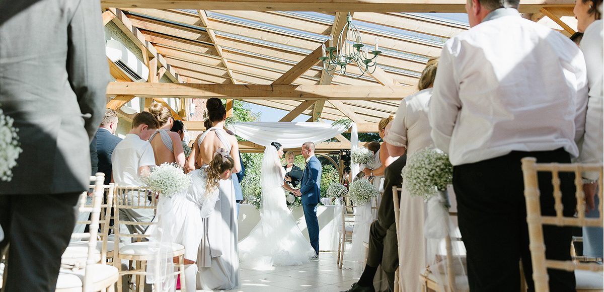 A bride and groom say their wedding vows in the Orangery at Gaynes Park