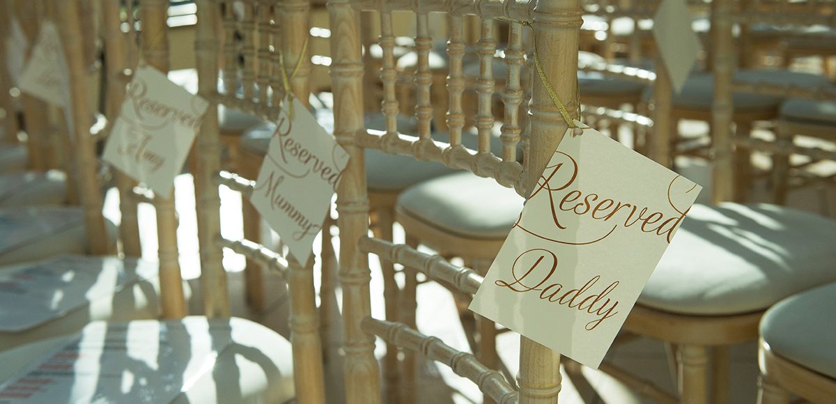 Reserved seating tags are attached to chairs in the Orangery ready for the wedding ceremony