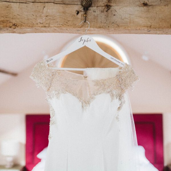 A bridal gown with delicate beaded details hangs in the Apple Loft Cottage at Gaynes Park