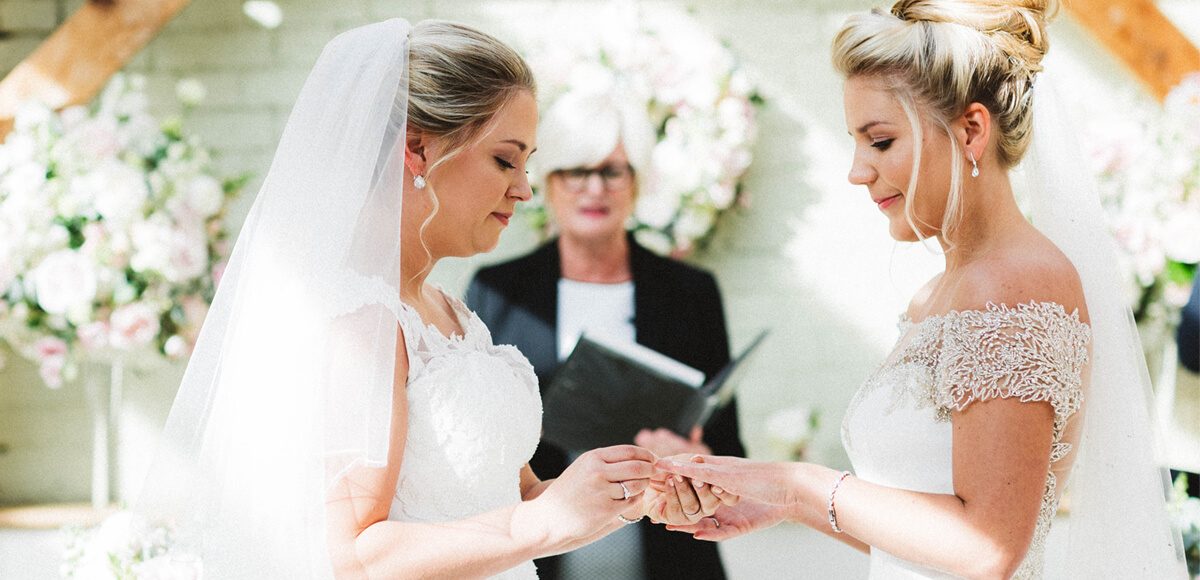The brides exchange rings and say I do during their wedding ceremony in the Orangery at Gaynes Park