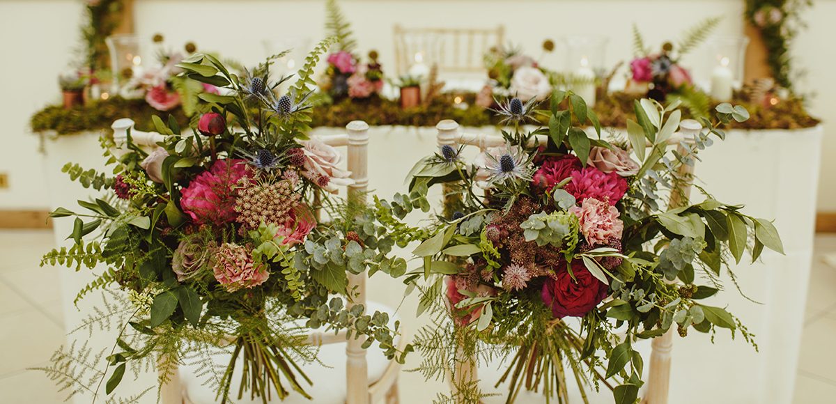 Rustic wedding flowers adored the chairs and table in the Orangery at Gaynes Park for a summer wedding ceremony