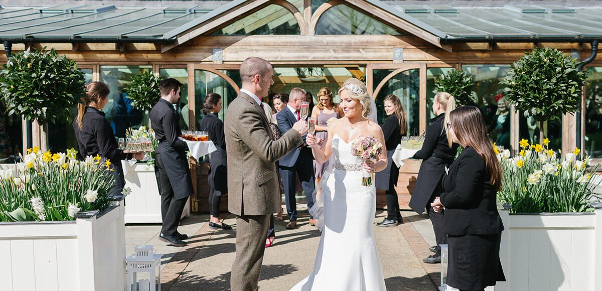 Newlyweds enjoy their wedding drinks reception in the beautiful Walled Gardens at Gaynes Park in Essex
