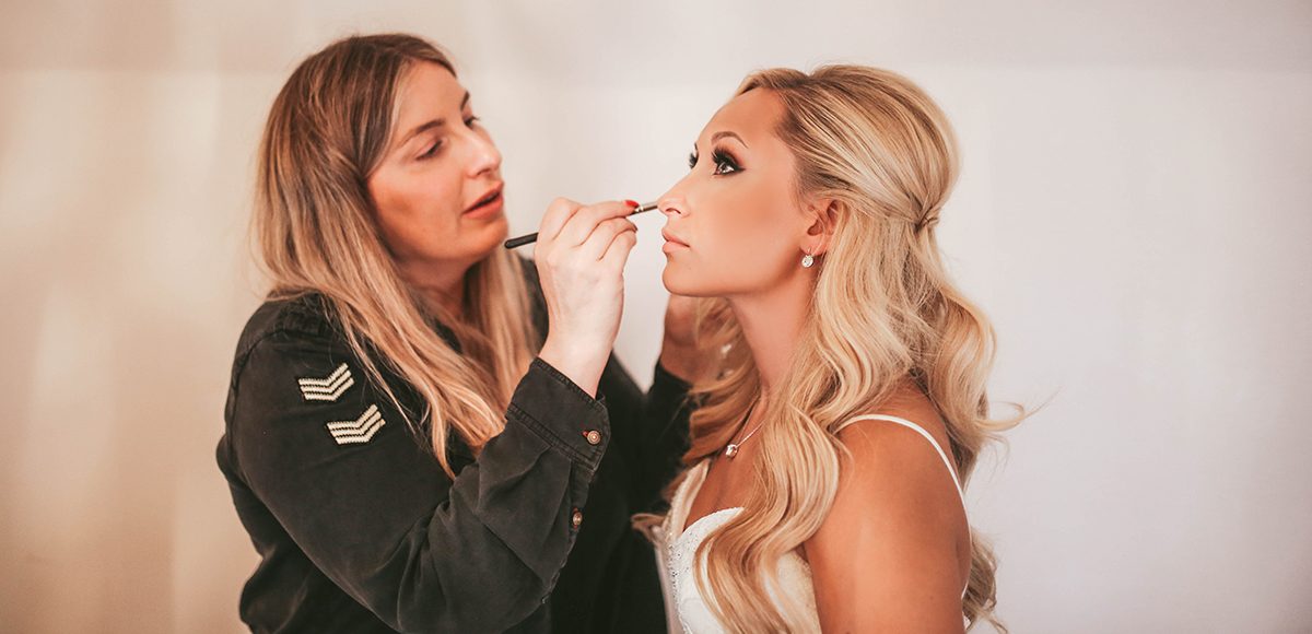 Bridal makeup is applied to the bride before her wedding ceremony at Gaynes Park
