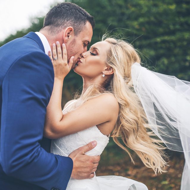 The couple share a kiss in the grounds at Gaynes Park wedding venue in Essex