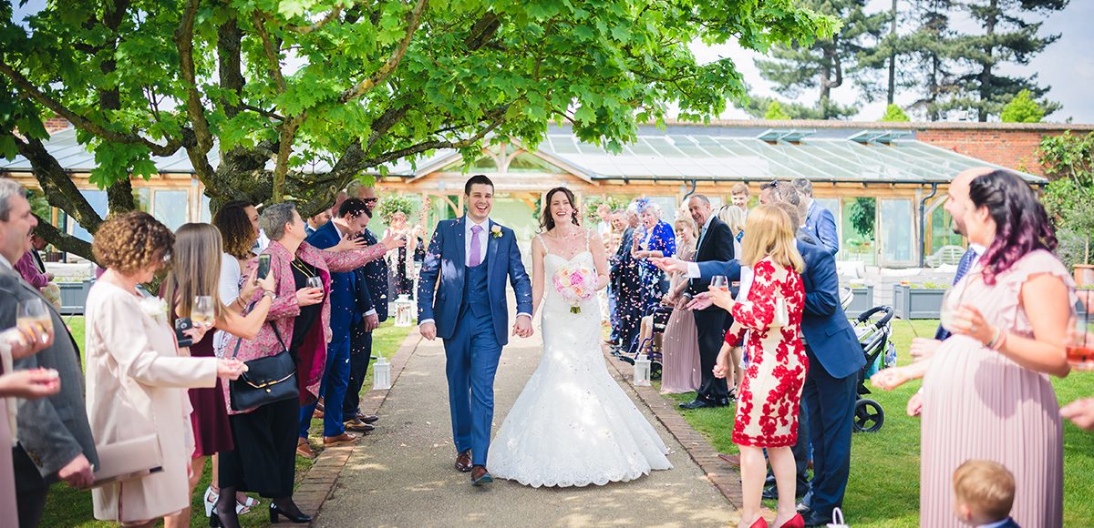 Newlyweds enjoy a confetti moment after their wedding ceremony at Gaynes Park in Essex
