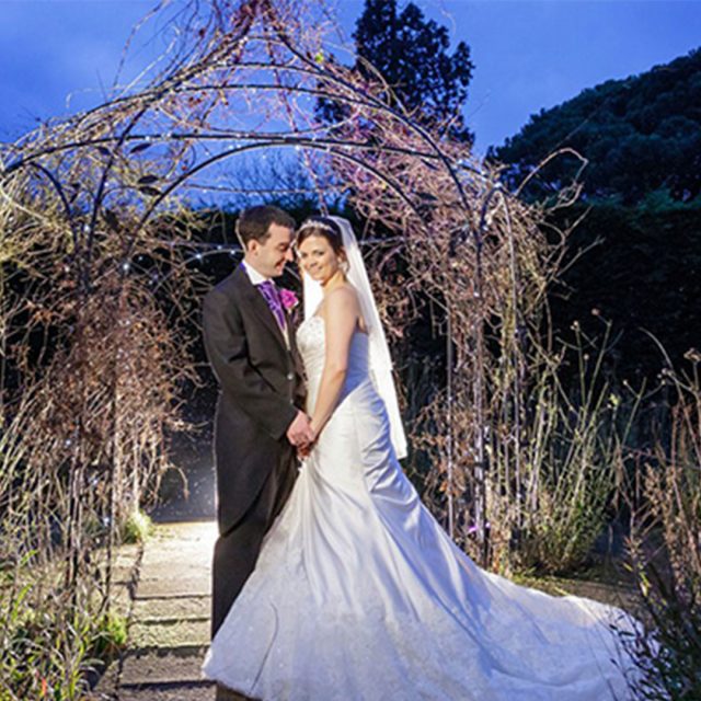 Bride and groom in the gardens of Gaynes Park at night.