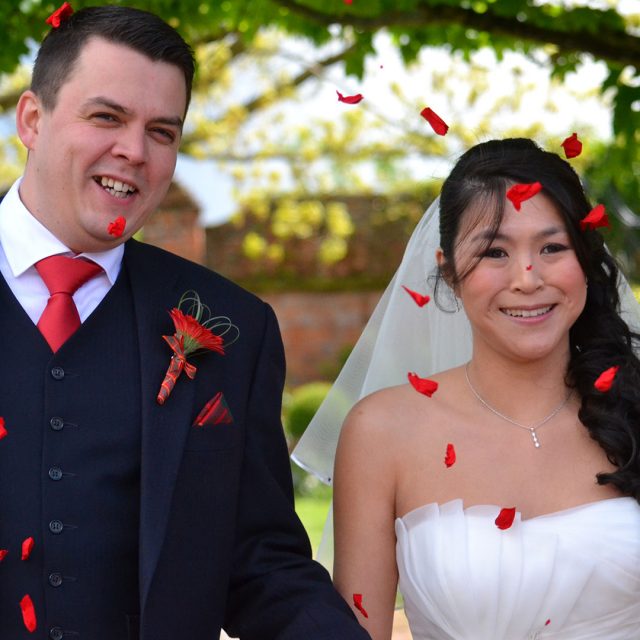 Red confetti photo of bride and groom after their Gaynes Park wedding ceremony