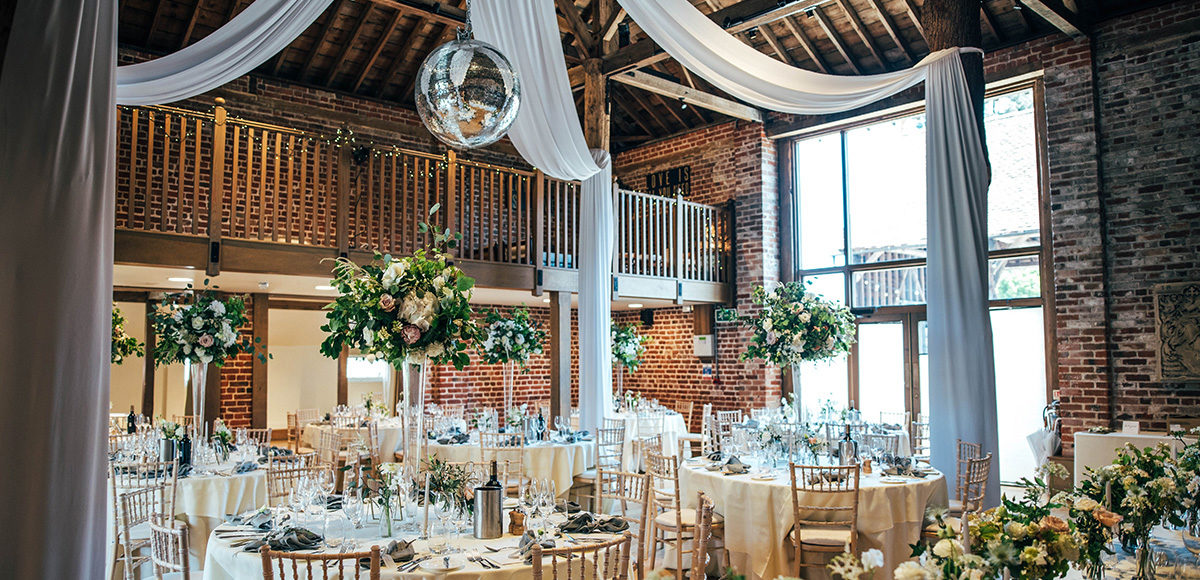 The Mill Barn at Gaynes Park is set up for a glamorous wedding reception