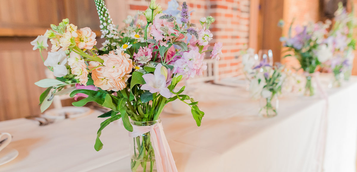 Wild wedding flowers in jam jars work perfectly in the Mill Barn at Gaynes Park