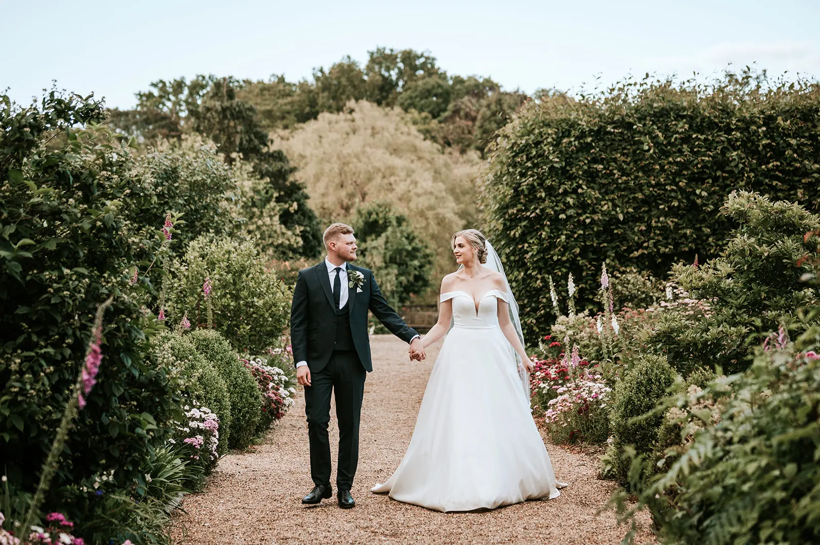 Couple walking down the long walk at Gaynes Park